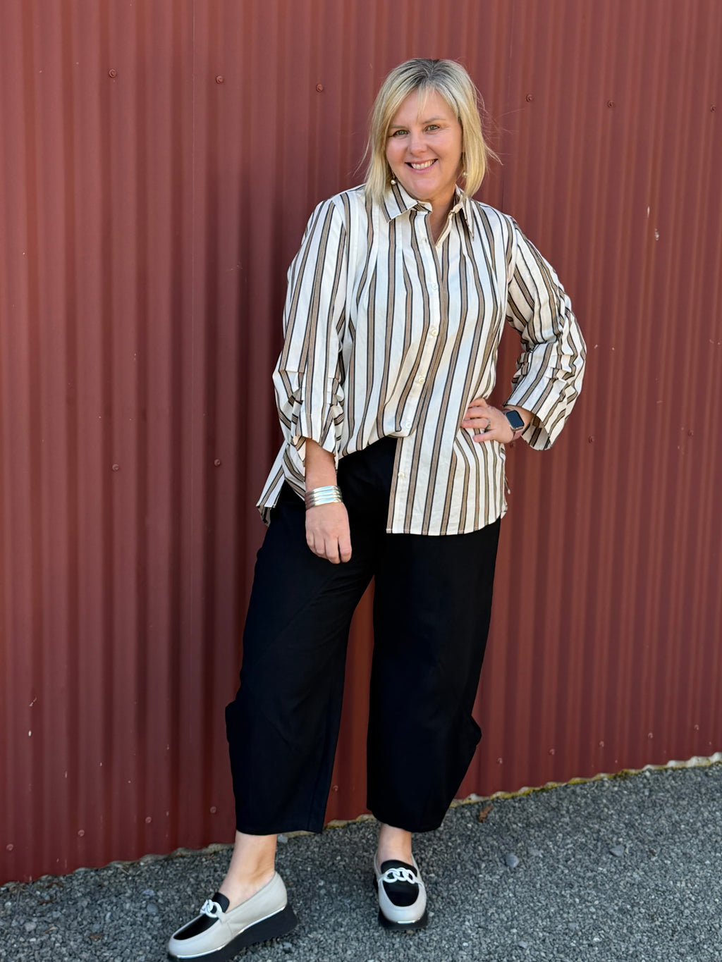 A modern striped cotton shirt by OBI, featuring a relaxed fit, button front, curved hem, longer back and beautifully pleated sleeves.