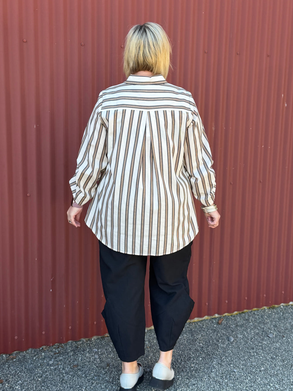 A modern striped cotton shirt by OBI, featuring a relaxed fit, button front, curved hem, longer back and beautifully pleated sleeves.