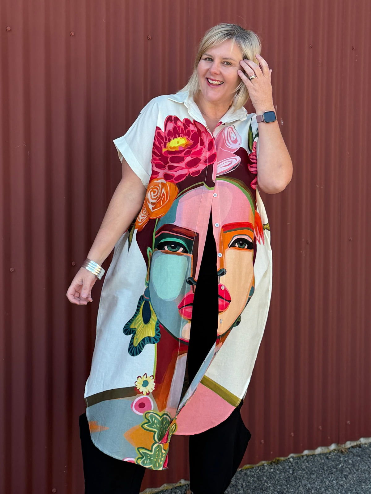 A true statement piece that’s bursting with personality. This longline shirt features a striking artistic face and floral print in vibrant pink, orange and green tones against a fresh white background.  Label Cindy C