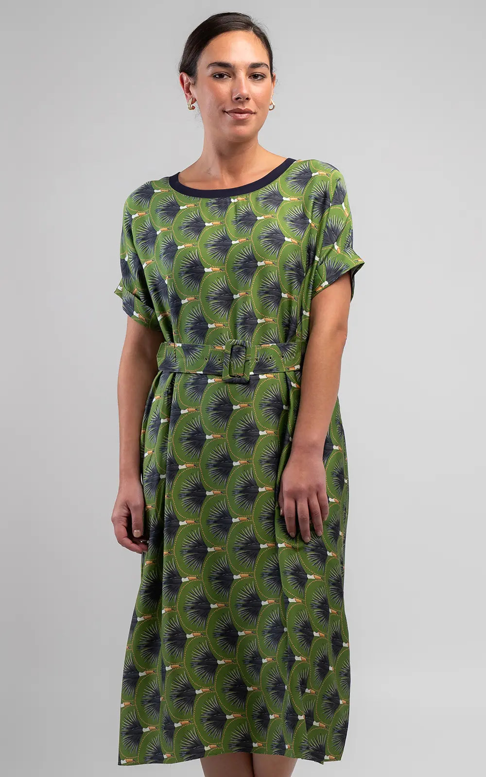 The Toucan Shift Dress features a vibrant olive print, relaxed fit, round neckline, cuffed sleeves, side pockets and a matching belt with buckle detail.