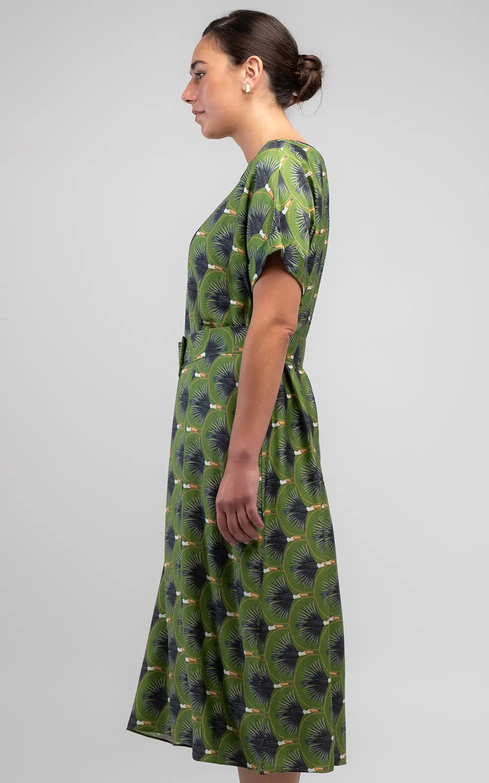 The Toucan Shift Dress features a vibrant olive print, relaxed fit, round neckline, cuffed sleeves, side pockets and a matching belt with buckle detail.