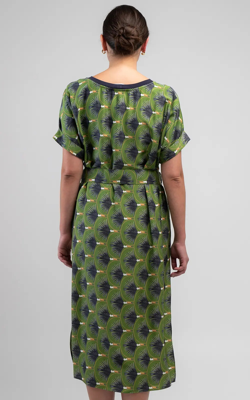The Toucan Shift Dress features a vibrant olive print, relaxed fit, round neckline, cuffed sleeves, side pockets and a matching belt with buckle detail.