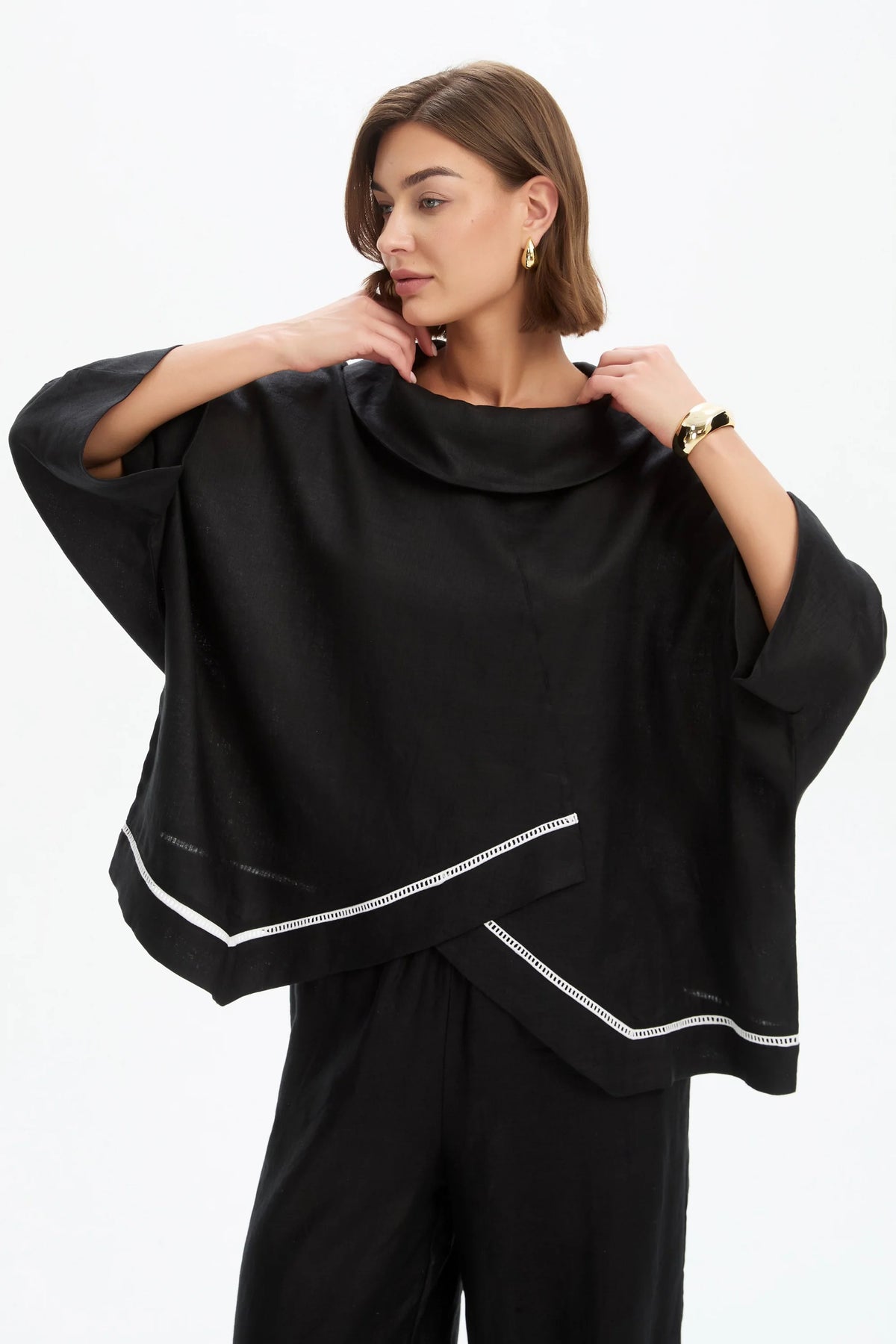 The Ladder Hem Cowl Neck Top brings a directional edge to everyday dressing with its considered, modern silhouette. Designed in a relaxed boxy fit, it features a soft cowl neckline and an asymmetric wrap front that creates subtle shape and movement. By Tirelli